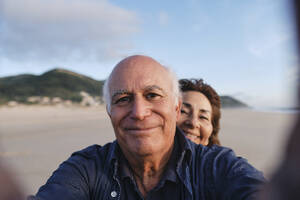 Älterer Mann und Frau fangen glücklichen Moment mit einem Selfie am Strand ein - ASGF04220