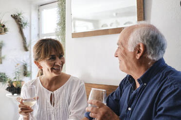 Smiling man and woman sitting with glasses of wine in cafe - ASGF04242