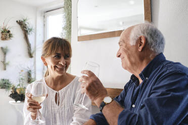 Happy senior man and woman sitting with glasses of wine in cafe - ASGF04243