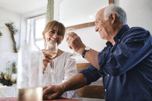 Happy man and woman sitting with glasses of wine in cafe - ASGF04244