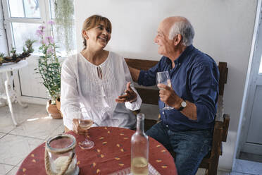 Glückliche ältere Frau im Gespräch mit einem Mann, der in einem Café sitzt - ASGF04247