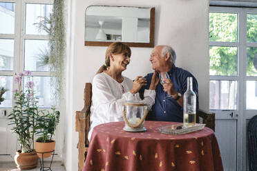 Cheerful senior woman and man sitting with wine glasses in cafe - ASGF04249