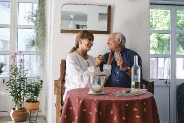 Fröhliche ältere Frau und Mann sitzen mit Weingläsern in einem Cafe - ASGF04249