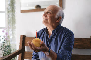 Lächelnder älterer Mann mit Muffin in der Hand - ASGF04261