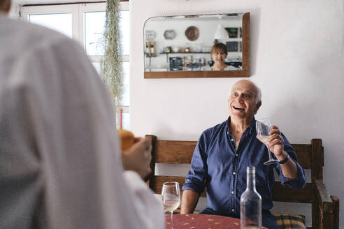 Überraschender älterer Mann, der ein Weinglas hält und eine Frau mit einem Cupcake betrachtet - ASGF04263