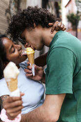 Happy couple sharing ice cream cone - PBTF00090