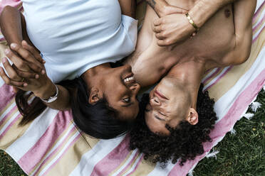 Glückliches Paar auf einer Decke auf einer Wiese liegend - PBTF00103