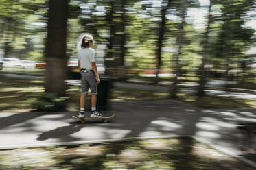 Junge fährt Skateboard auf dem Fußweg im Park - ANAF01841