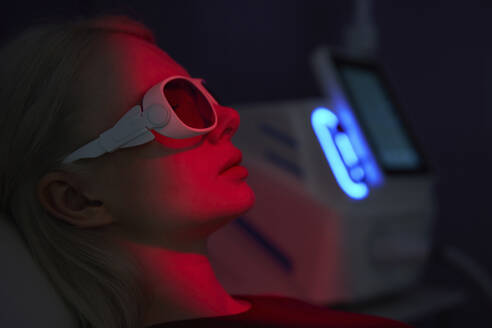Junge Frau trägt Virtual-Reality-Headset inmitten von rotem Neonlicht - AZF00556