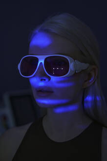 Junge Frau trägt Virtual-Reality-Headset mit blauem Neonlicht - AZF00558
