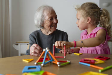 Lächelnde Großmutter und Enkelin spielen ein Freizeitspiel zu Hause - SVKF01550