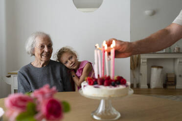 Father lighting birthday candles with family at home - SVKF01552