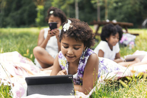 Schwestern verbringen ihre Freizeit mit drahtloser Technologie im Garten - PBTF00113