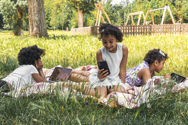 Happy sisters spending time with wireless technology in garden - PBTF00115