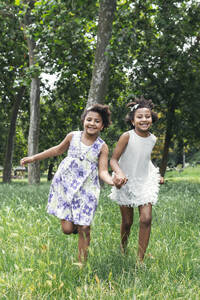 Lächelnde Zwillingsschwestern laufen im Garten - PBTF00116