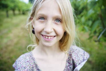 Glückliches Mädchen mit blondem Haar im Garten - NJAF00471