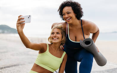 Zwei Frauen halten ihre glücklichen Momente nach einem Yoga-Workout an der Strandpromenade fest und genießen einen gesunden und lustigen Tag im Freien - JLPSF30614