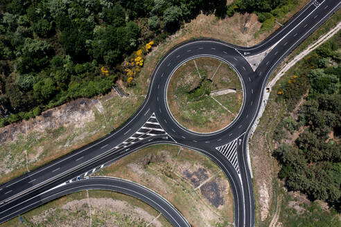 Aerial view of infrastructure development of asphalt circle road with facility to allow transport vehicles move into desired directions while surrounded with green forest trees - ADSF45771