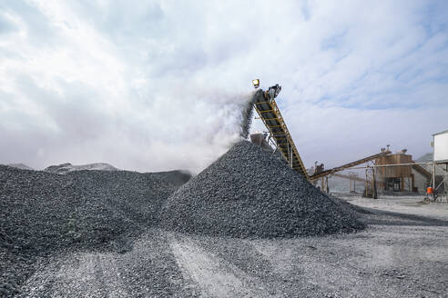 Rock crusher with conveyor belt heavy machinery of stone extracting for covering railway tracks in quarry during overcast weather - ADSF45785