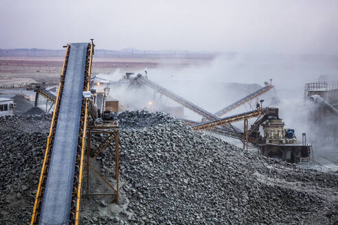 Industrial heavy machines with conveyor belts crushing stones for covering railway tracks in quarry with dirt and dust - ADSF45787