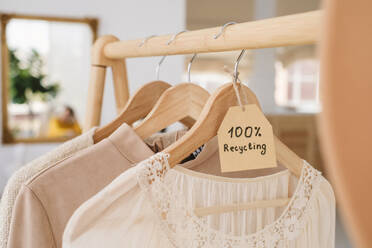 Beige clothes on hangers hanging on wooden rack with paper tag with 100NinaGili_ID14258_429415_015.jpg - ADSF45849