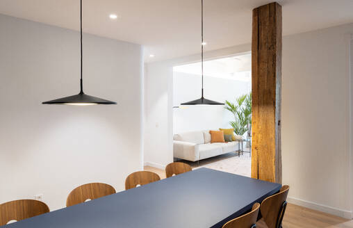 Interior design of a spacious dining room with a blue table and chairs in a modern and bright flat - ADSF45861