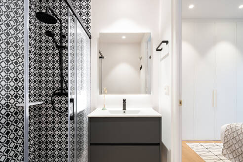 Interior of bathroom with glass shower cabin and white ceramic sink with faucet and mirror at new home - ADSF45864