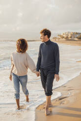 Couple holding hands and walking at beach - JOSEF20340