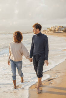 Paar hält sich an den Händen und geht am Strand spazieren - JOSEF20340