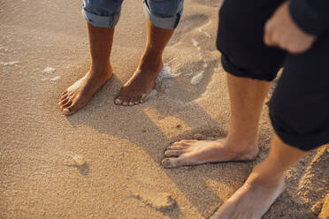 Couple standing barefoot on sand at beach - JOSEF20344