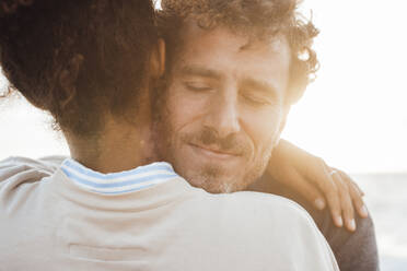 Man embracing girlfriend at beach - JOSEF20350