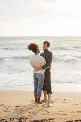 Loving couple together standing on coastline at beach - JOSEF20354