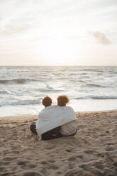 Couple wrapped in blanket and spending leisure time at beach - JOSEF20360