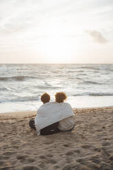 In eine Decke eingewickeltes Paar, das seine Freizeit am Strand verbringt - JOSEF20360