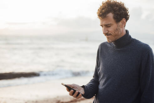 Mann benutzt Smartphone am Strand - JOSEF20377