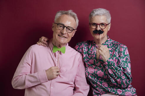 Happy senior couple posing with fake moustache and bowtie - RBF09126