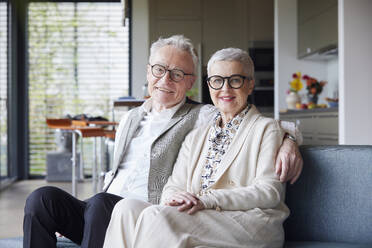 Porträt eines glücklichen älteren Paares, das zu Hause auf der Couch sitzt - RBF09156