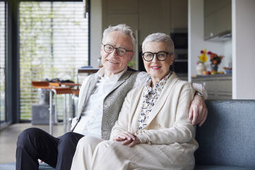 Portrait of happy senior couple sitting on couch at home - RBF09156