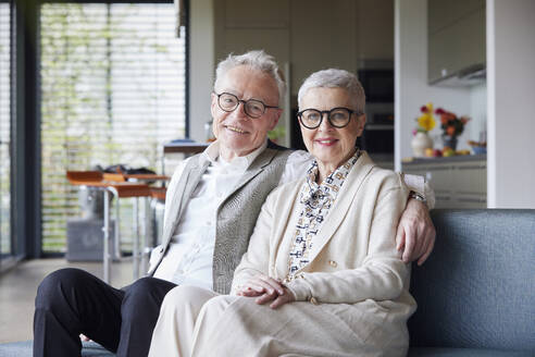 Portrait of happy senior couple sitting on couch at home - RBF09156