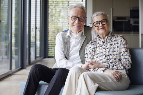 Porträt eines glücklichen älteren Paares, das zu Hause auf der Couch sitzt - RBF09158