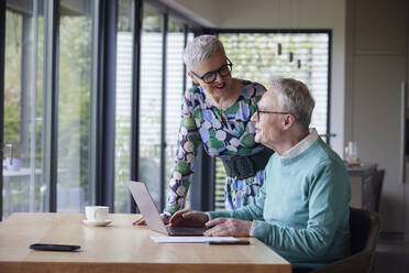 Senior couple using laptop at table at home - RBF09207