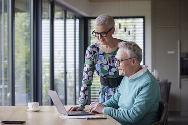 Senior couple using laptop at table at home - RBF09208