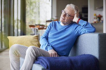 Entspannter älterer Mann sitzt zu Hause auf der Couch - RBF09242