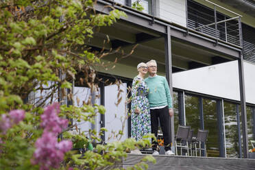 Senior couple standing in front of their home - RBF09248