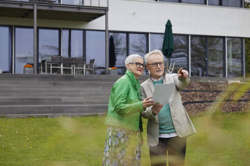 Senior couple standing in garden makong plans - RBF09250