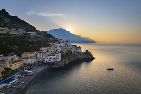 Sea with nautical vessel near town at sunrise - LOMF01375