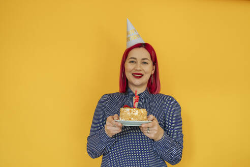 Smiling woman with dyed hair holding birthday cake - OSF01915