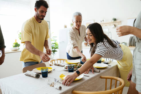 Happy family setting table in kitchen - EBSF03680