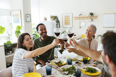 Family raising toast on dining table in kitchen - EBSF03682