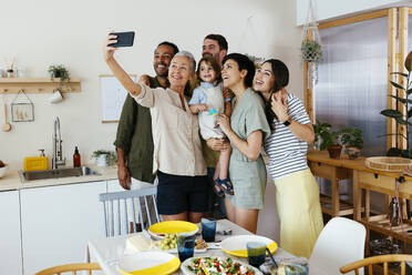 Eine glückliche Familie hält einen Moment in der Küche mit einem Selfie mit ihrem Smartphone fest - EBSF03684